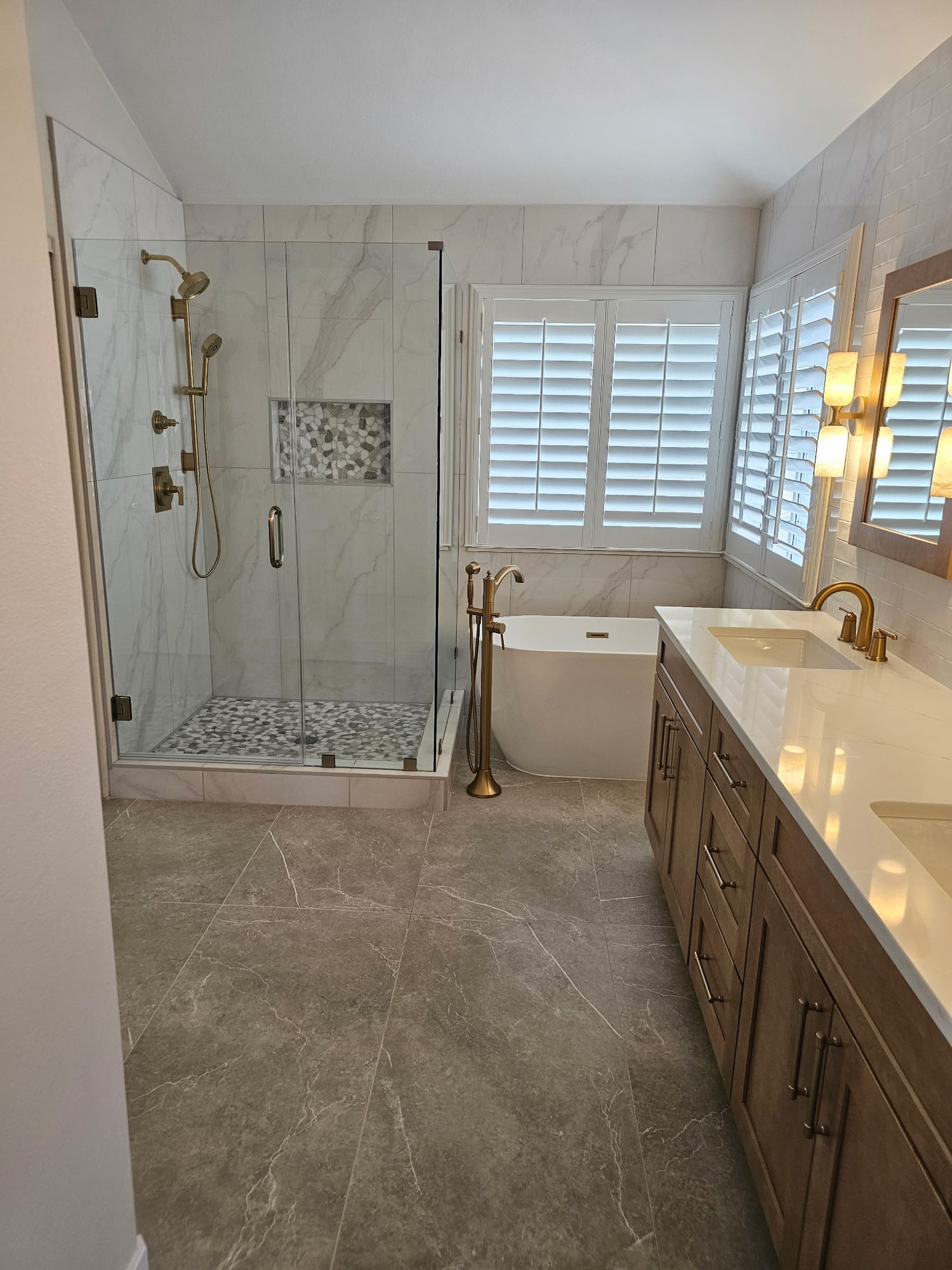 Primary bath after: frameless glass shower, freestanding tub and gold fixtures